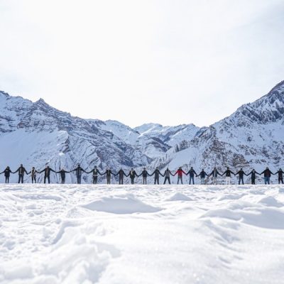 The people holding hands as a sign of peace with the mountains in the background in winter